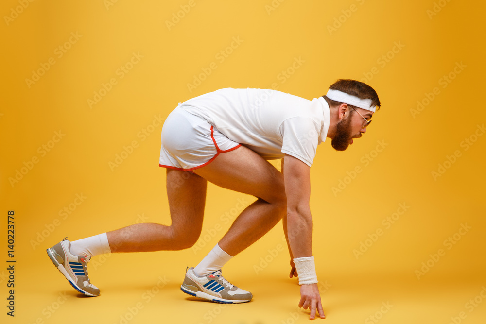 Side view of sportsman in sunglasses preparing to run Side view of sportsman in sunglasses preparing to run