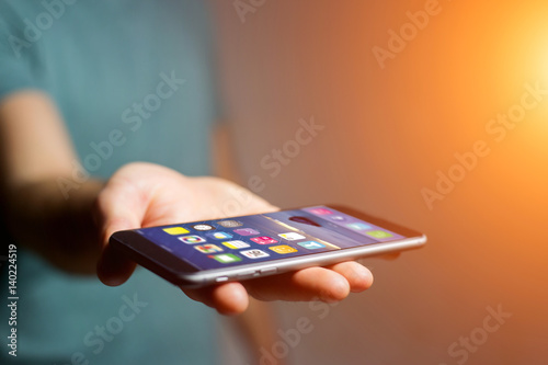 Hand holding black smartphone with operating system screen