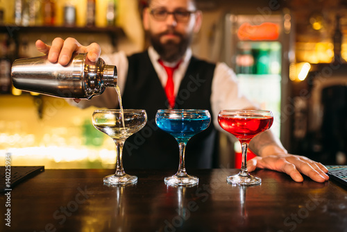 Bartender making alcohol beverages in nightclub photo