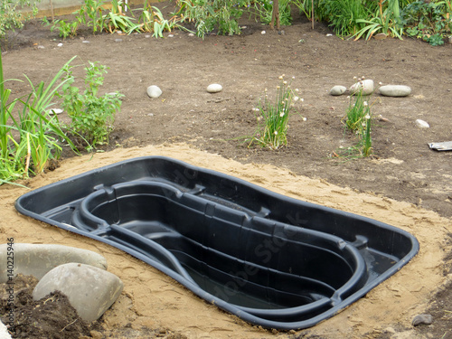 Testing of an installed preformed plastic pond insert filled with some water in the summer garden