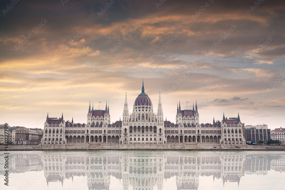 Parliament building in Budapest, Hungary on a cloudy day at sunset. Building facade with reflection in water