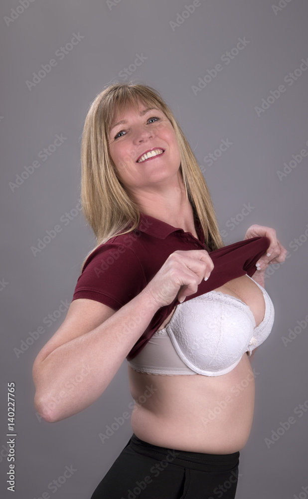 Woman pulling a tight fitting shirt over her bra Stock Photo