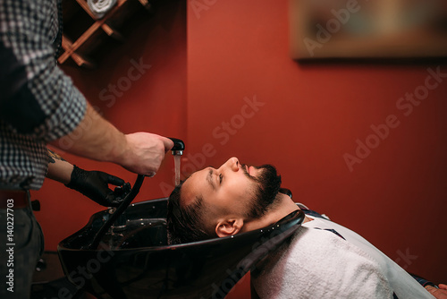 Barber washes the hair of a client man
