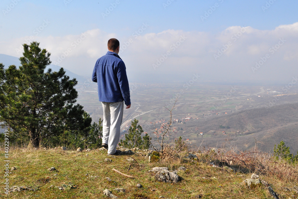 Young man standing on top of the hill over the city Young man standing on top of the hill over the city
