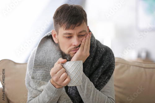 Young ill man drinking hot ...