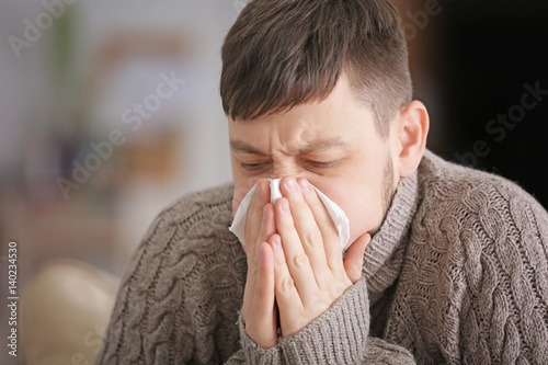 Young ill man blowing nose ...