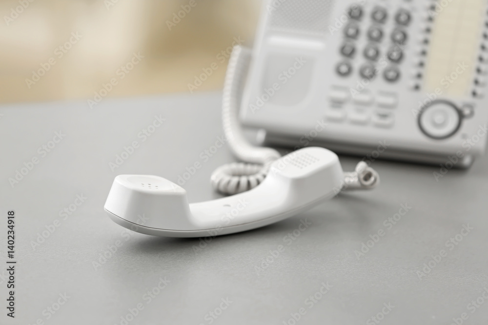 Telephone with picked up receiver on table in office