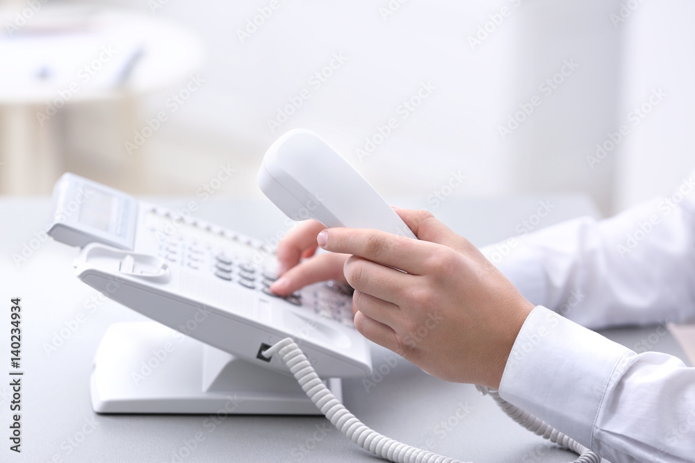 Hands of man dialing telephone number in office Hands of man dialing telephone number in office