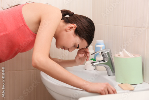 Young vomiting woman near s...