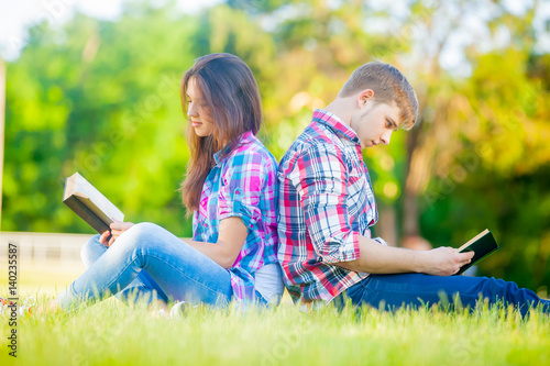 beautiful cute couple sitting on the field and reading their books
