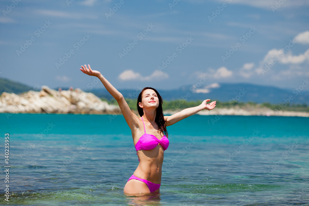 beautiful young woman standing in the clear and calm sea in sunny Greece