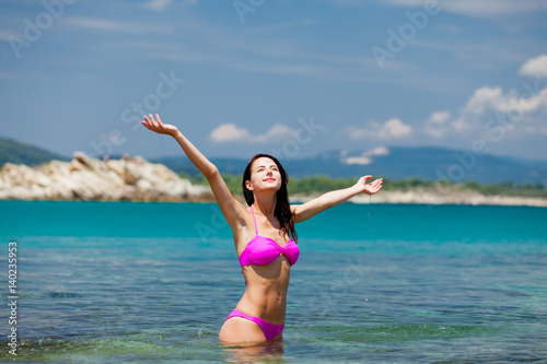 beautiful young woman standing in the clear and calm sea in sunny Greece