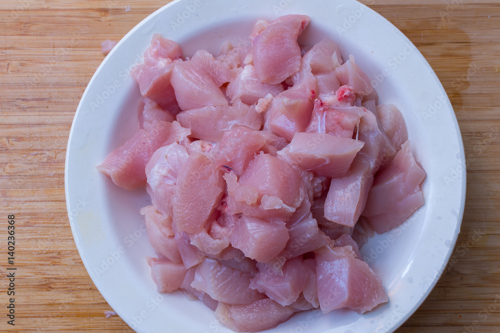 Chicken sliced fillet in white plate on wooden cutting board Chicken sliced fillet in white plate on wooden cutting board