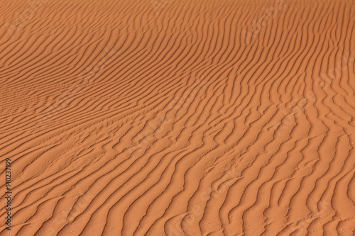 Rippled red brown desert or beach sand texture. Wavy background.