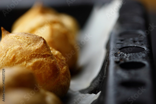 French dessert of profiteroles(eclair) on tray choux pastry.Closeup.Selective focus photo