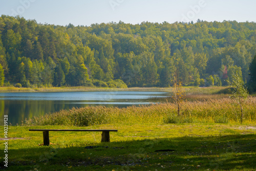 Calm lake and a bench in the autumn