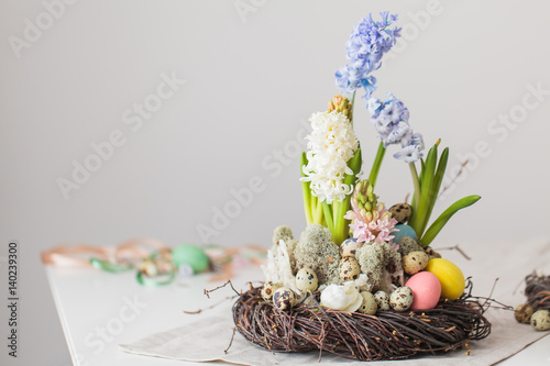 Flower arrangement in a nest with easter eggs on a white table