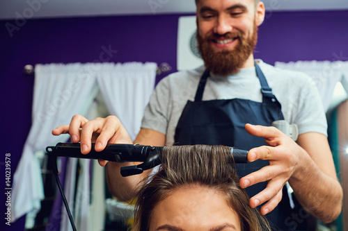 Close-up concept hairdresser barbershop.Barber stylist makes a hair curl.