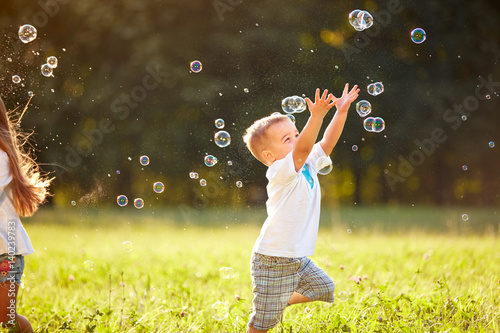 Male child catches soap bubbles in nature