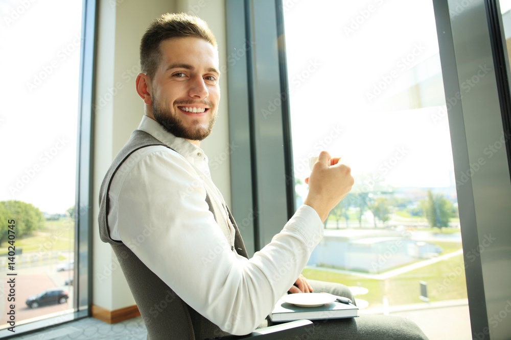 Businessman having a coffee break and relaxing at window Businessman having a coffee break and relaxing at window