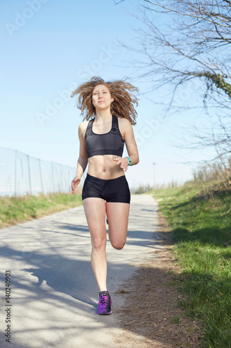 Young attractive sport girl running in park