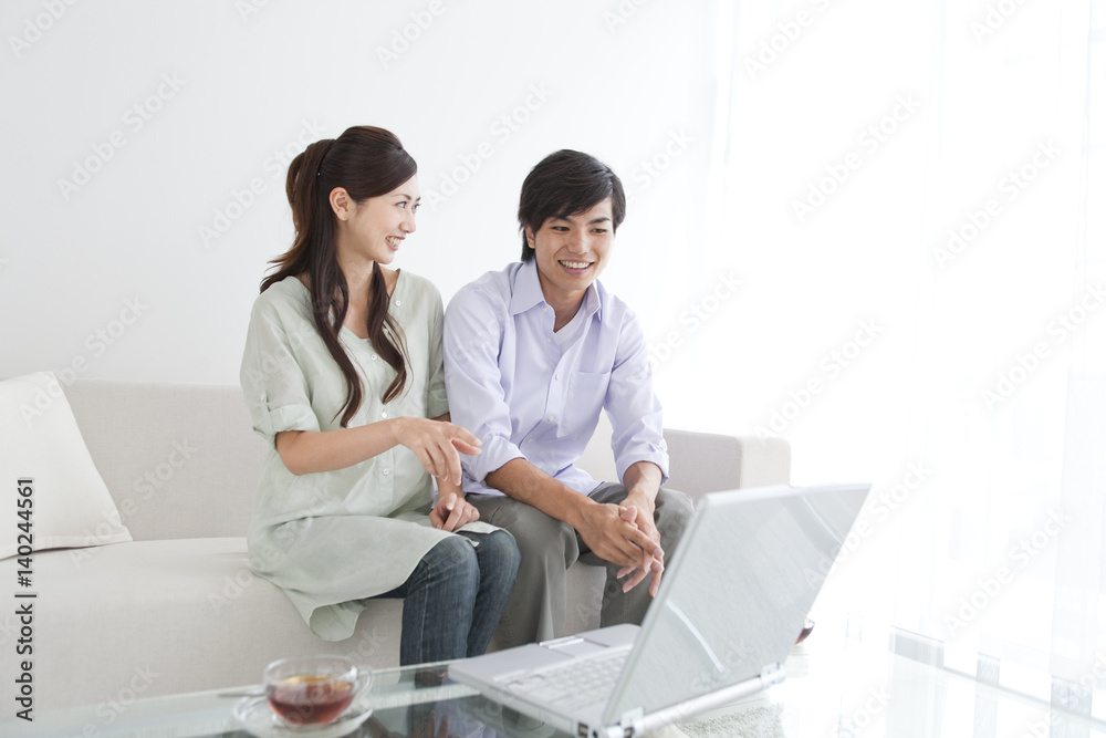 Young couple looking at laptop monitor, sitting on sofa Young couple looking at laptop monitor, sitting on sofa