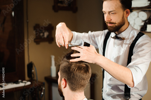 Master cuts hair and beard of men in the barbershop