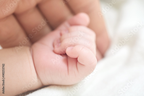 A parent holding the hand of a newborn baby