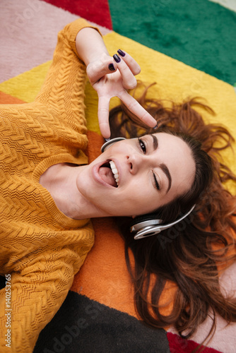 Young pretty girl in headphones winking and enjoying music