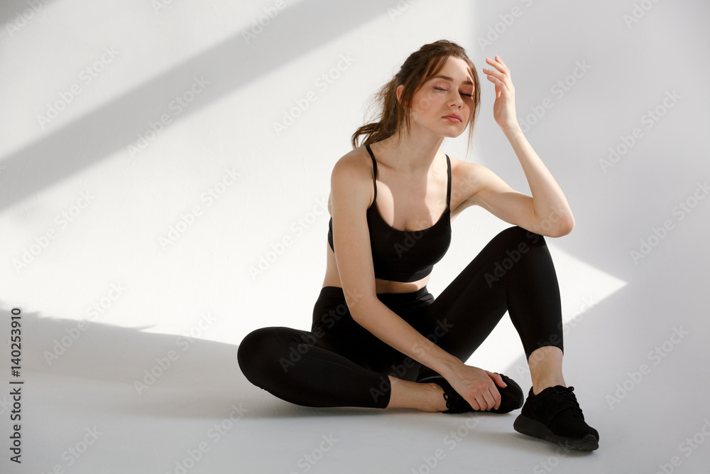 Sports woman resting after workout while sitting on the floor Sports woman resting after workout while sitting on the floor