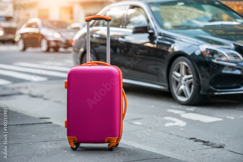 Fotografia Luggage bag on the city street ready to pick by airport transfer taxy car