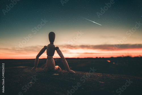 Omino seduto su un muro che immagina il futuro guardando il tramonto. photo