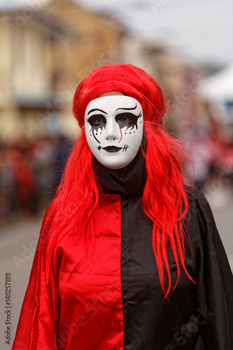 Masque blanc sur costume noir et rouge pour la journée des diables rouges du carnaval de Cayenne en Guyane française