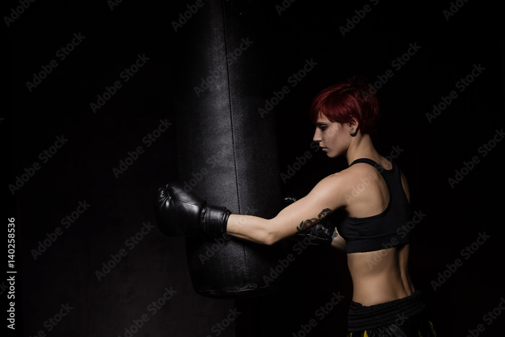 Athlete boxer woman punching a punching bag
