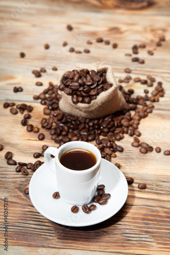 cup of coffee with grains on the wooden background