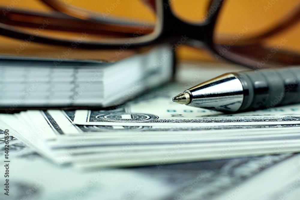 Fototapeta premium Ball pen and small notebook on US dollar banknote