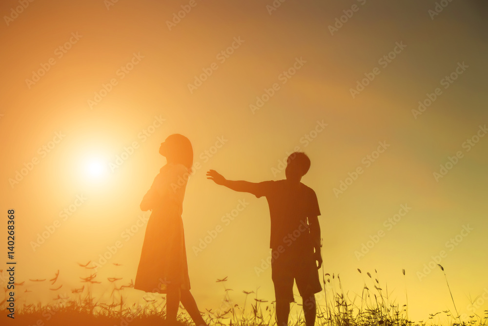 a silhouette of a man and woman holding hands with each other, walking together