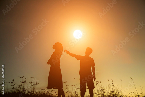 a silhouette of a man and woman holding hands with each other, walking together