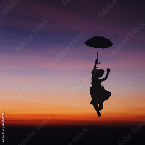 Umbrella little girl jumping and sunset silhouette. © stockphotokae