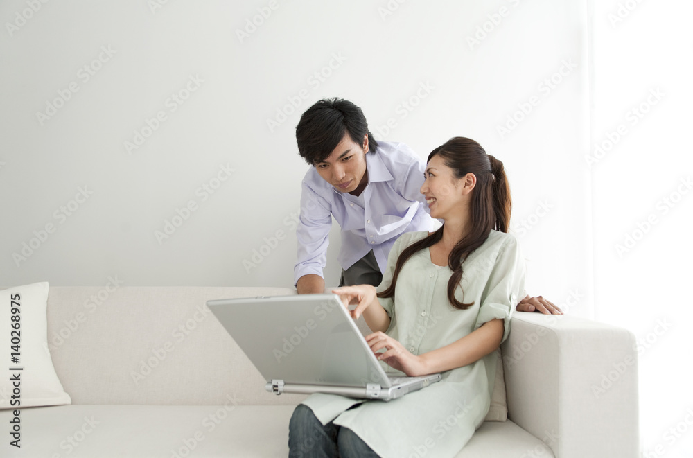 Young couple looking at laptop monitor, sitting on sofa Young couple looking at laptop monitor, sitting on sofa