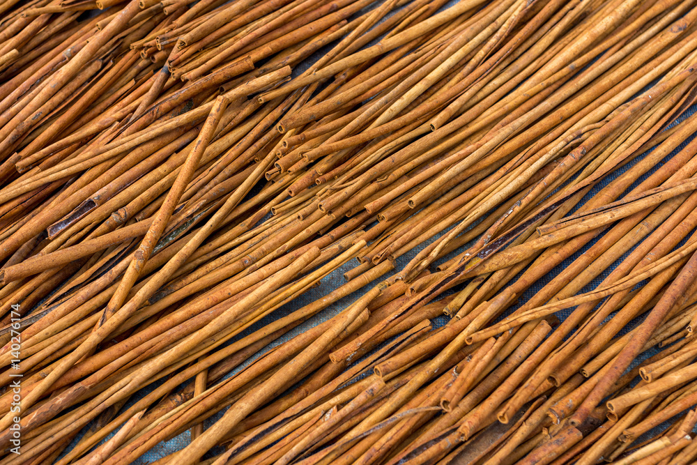 Fresh Cinnamon sticks out in the street drying in the midday sun. Viewed from above. Fresh Cinnamon sticks out in the street drying in the midday sun. Viewed from above.
