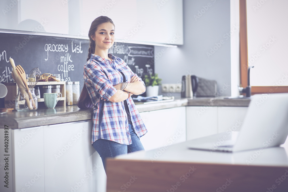 Portrait of young woman standing with arms crossed against kitchen background Portrait of young woman standing with arms crossed against kitchen background