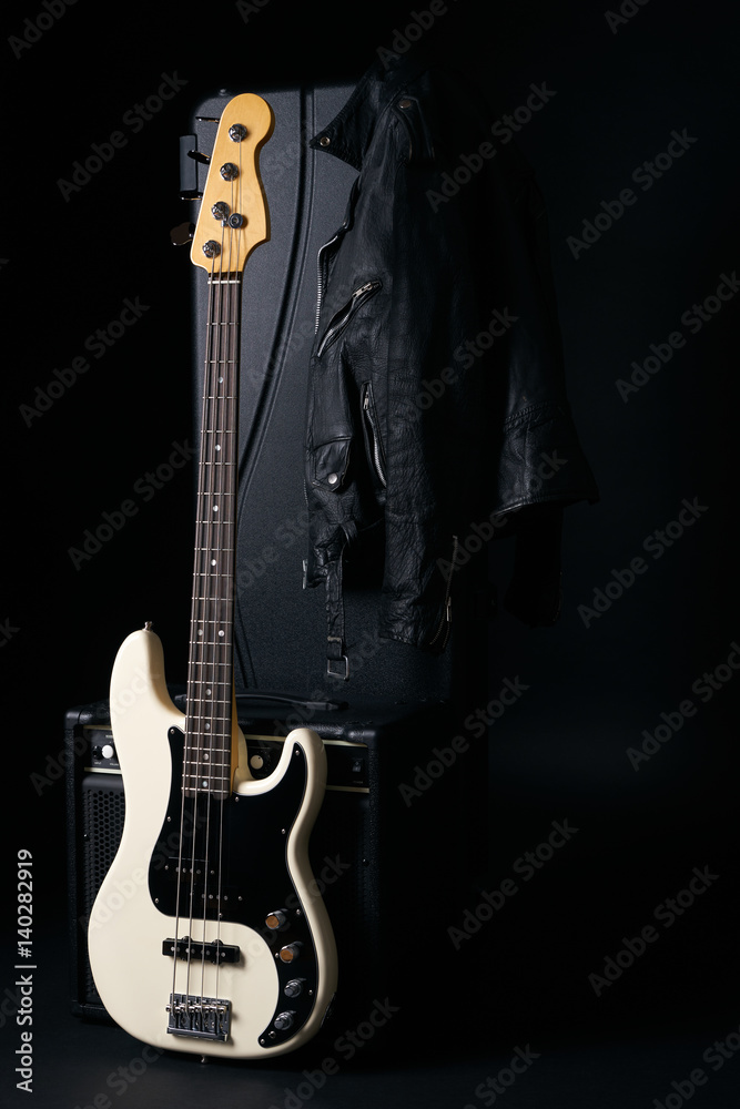 Fototapeta premium Black and white electric bass guitar with amplifier,hard case and Leather biker jacket on black background