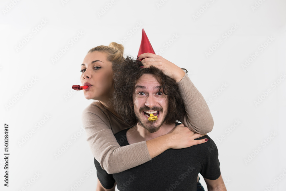 couple in party hats blowing in whistle couple in party hats blowing in whistle