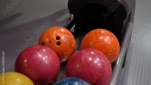 Close-up of varicolored bowling balls, man takes ball. Man is playing bowling slow motion