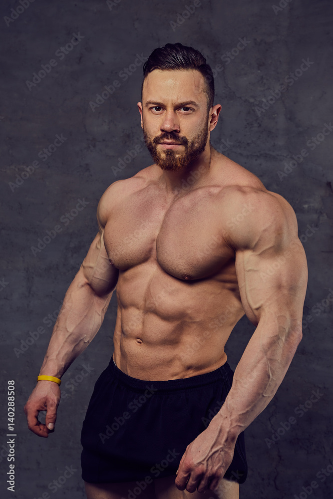 Shirtless bearded bodybuilder over grey background. Shirtless bearded bodybuilder over grey background.