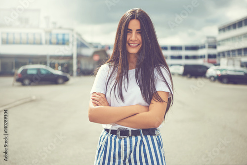 Woman with striped pants and folded arms outside