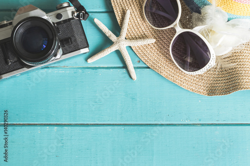 Beach hat and retro camera on wooden background