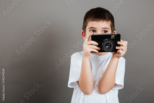 Handsome little boy standing and using photo camera