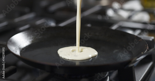 preparing blini or crepes batter pouring on hot pan, 4k photo